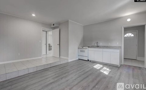 A spacious kitchen with white cabinets and a grey floor.