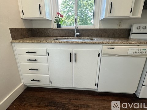 A kitchen with white cabinets and a granite countertop.