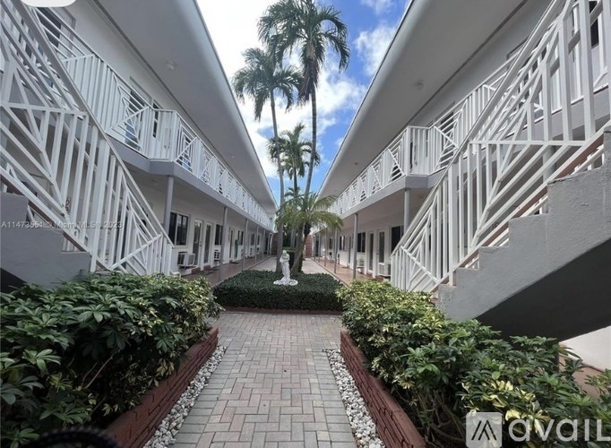 A white building with a balcony and a statue in the middle of a walkway.