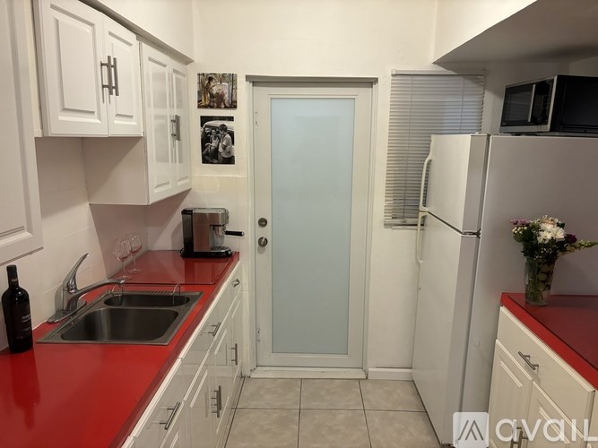 A kitchen with white cabinets and a red countertop.
