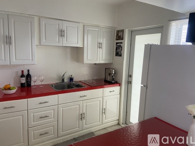 A kitchen with white cabinets and a red countertop.