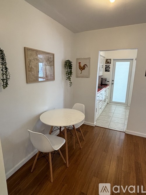 A white table with two chairs is in a room with wooden floors and white walls.