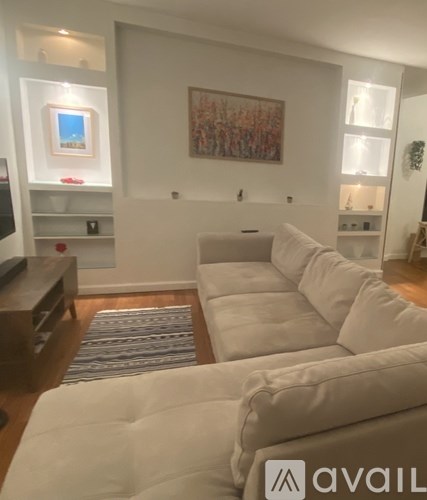 A living room with a couch, a rug, and a painting on the wall.