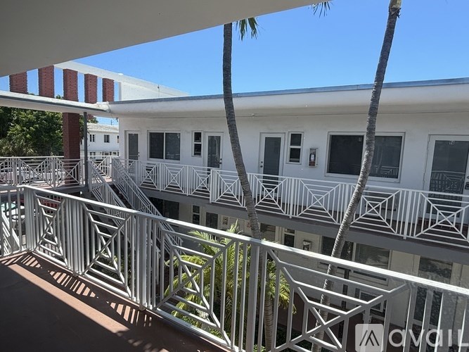 A white building with a balcony and a palm tree.