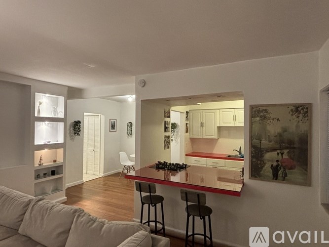 A modern kitchen with a bar stool and a painting on the wall.