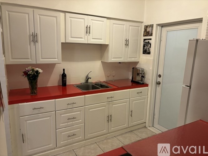 A kitchen with white cabinets and a red countertop.