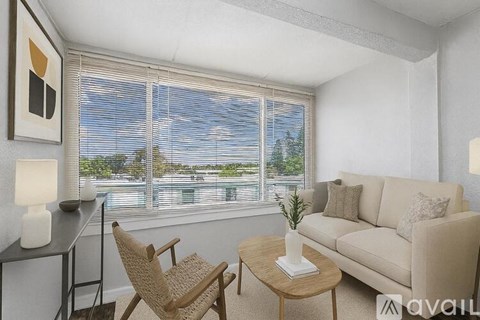 A living room with a couch, chair, and table with a vase of flowers on it.