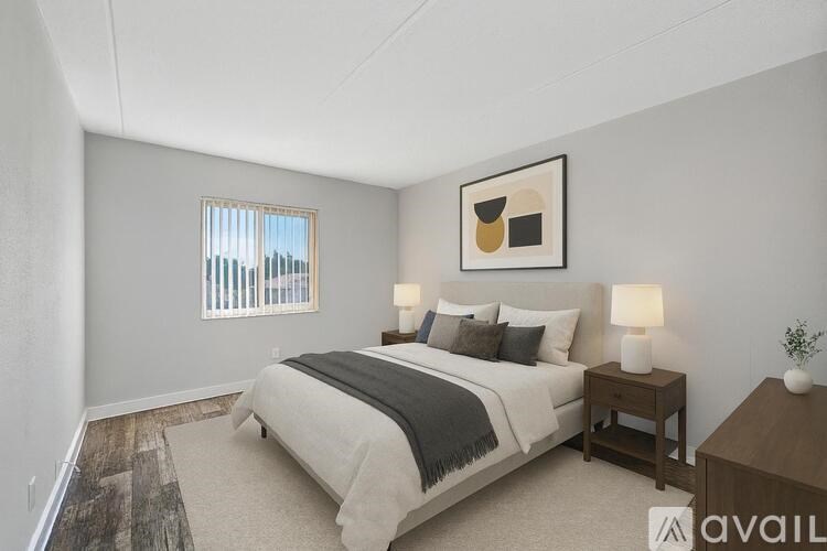 A bedroom with a large bed, two nightstands, and a framed picture on the wall.