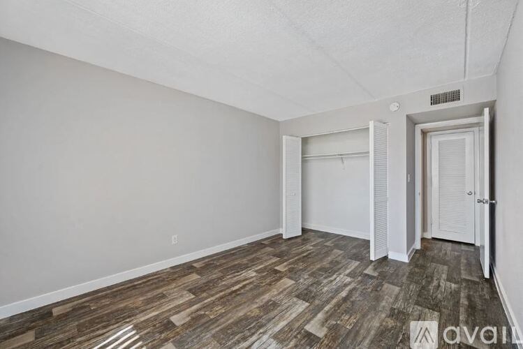 A room with wooden flooring and white walls, with a door on the right.