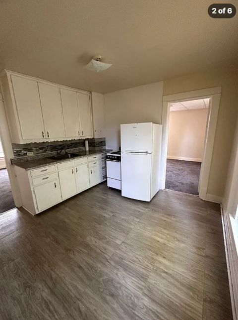 A kitchen with white cabinets and a white refrigerator.