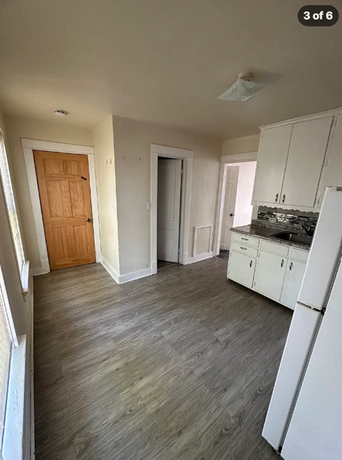 A kitchen with white cabinets and a wooden door.