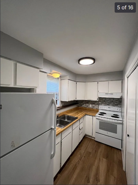 A kitchen with white appliances and wooden floors.