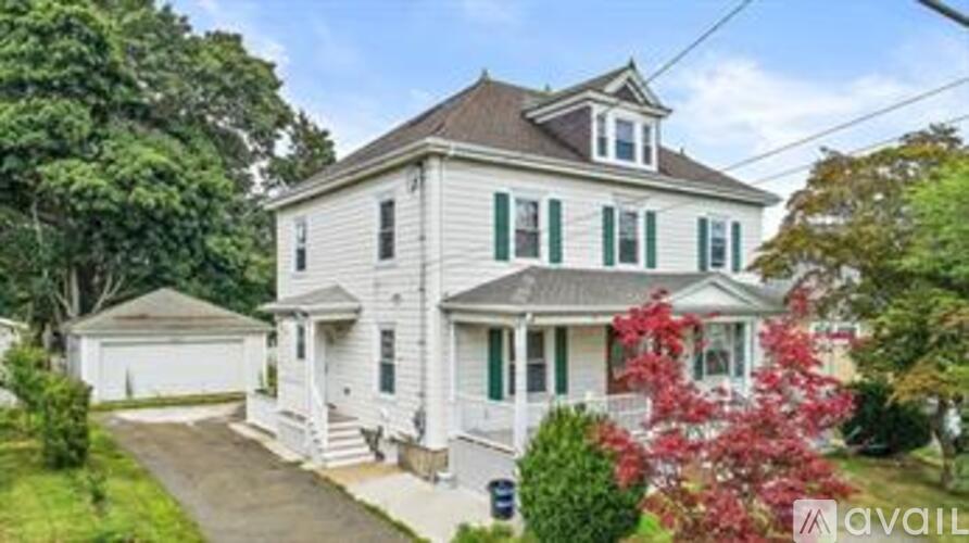 A white house with green shutters is for sale.