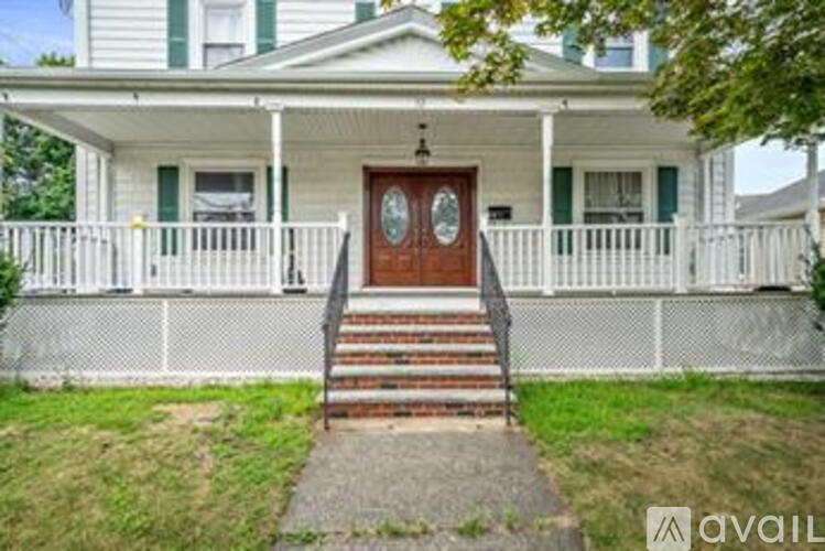 A white house with a brown door and a porch.