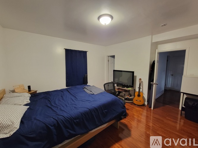 A bedroom with a bed, a guitar, and a television.