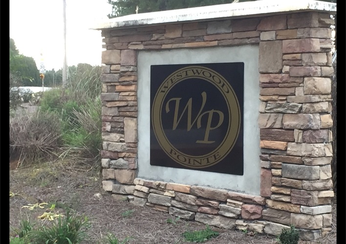 A sign with the letters WP on it is mounted on a stone wall.