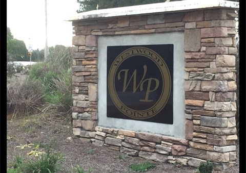 A sign with the letters WP on it is mounted on a stone wall.