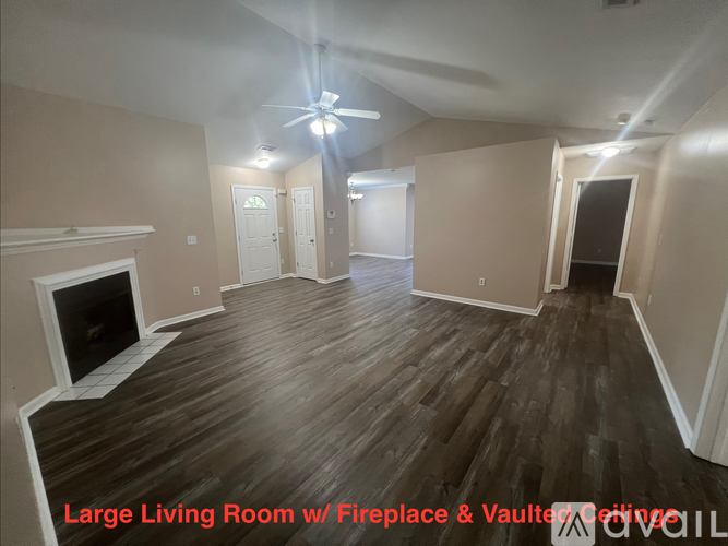 A spacious room with a fireplace and wooden flooring.