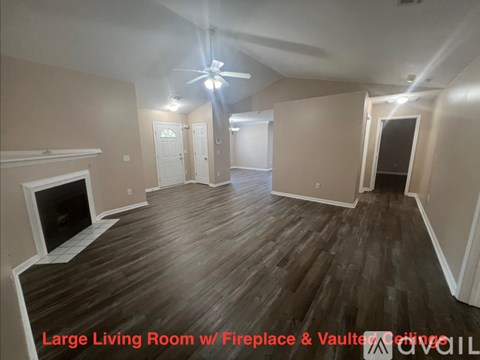 A spacious room with a fireplace and wooden flooring.