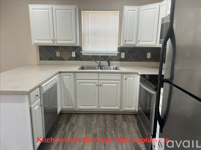 A kitchen with white cabinets and a wooden floor.