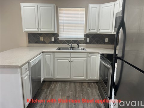 A kitchen with white cabinets and a wooden floor.