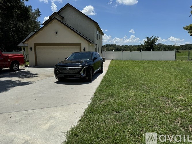 A black car is parked in a driveway in front of a house.