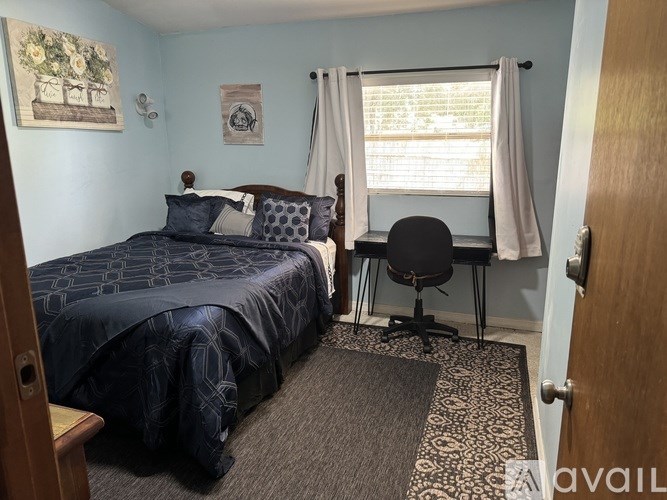 A bedroom with a bed, desk, and chair.