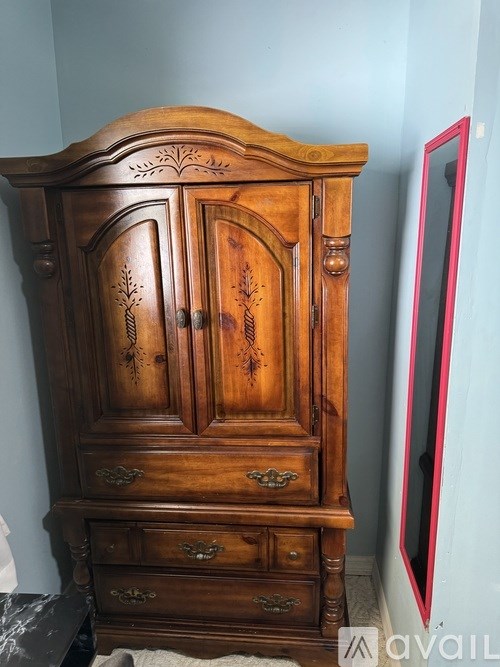 A wooden armoire with a mirror on the right side.