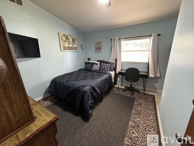 A bedroom with a bed, chair, and window.