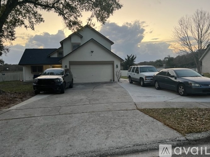 A house with a garage and a driveway with two cars parked in front.
