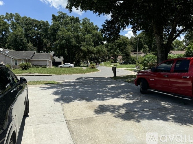 A red pickup truck is parked on the right side of a street.