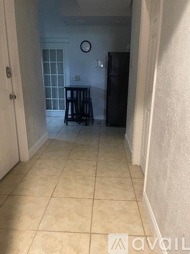 A kitchen with a fridge and a clock on the wall.