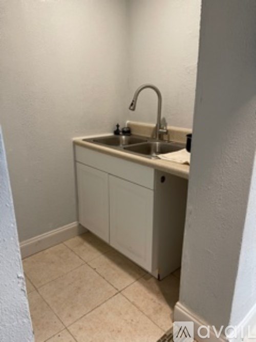 A small white kitchen with a sink and a cabinet.
