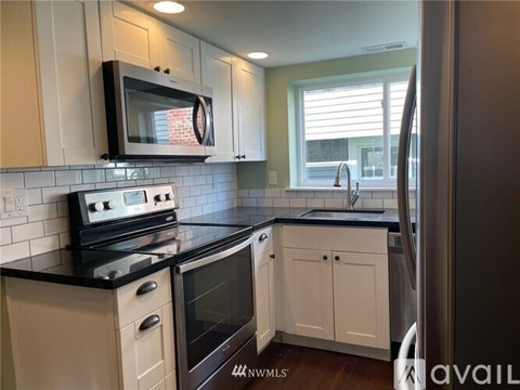 A kitchen with white cabinets and black countertops.