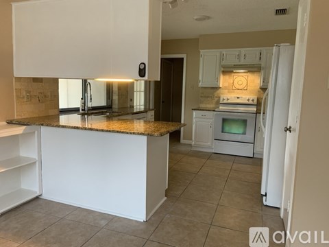 A kitchen with white cabinets and a granite countertop.