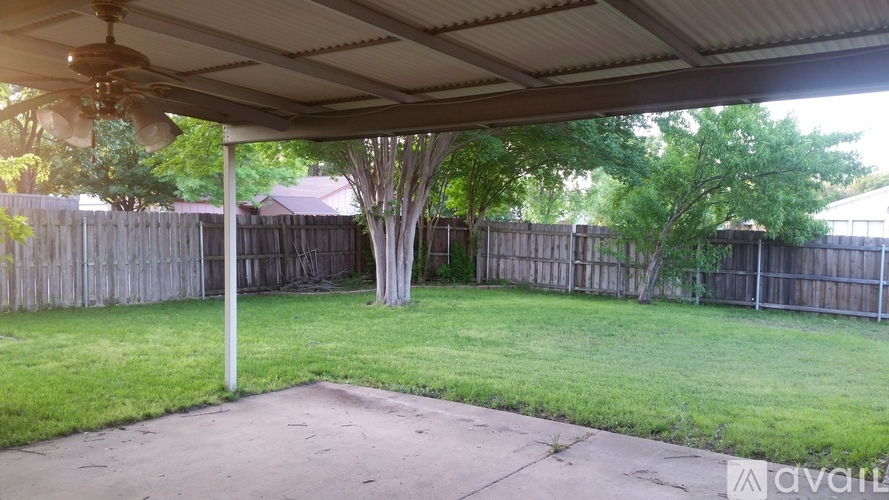 A backyard with a patio and a tree.