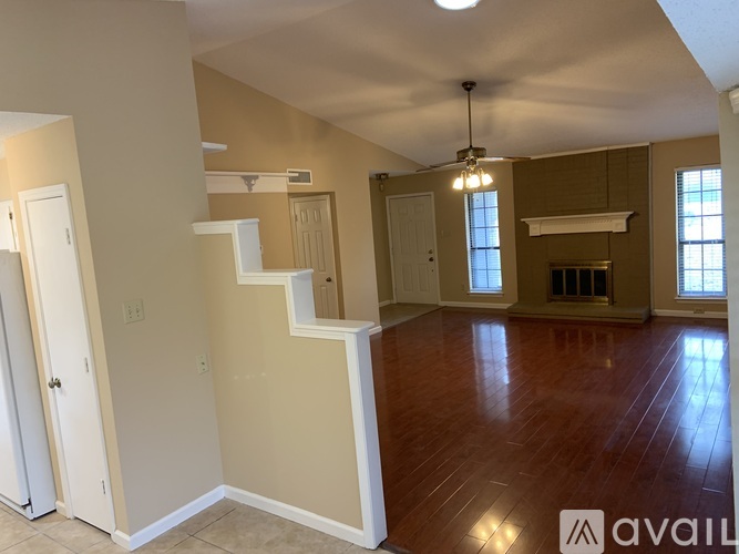 A spacious room with a staircase and a ceiling fan.