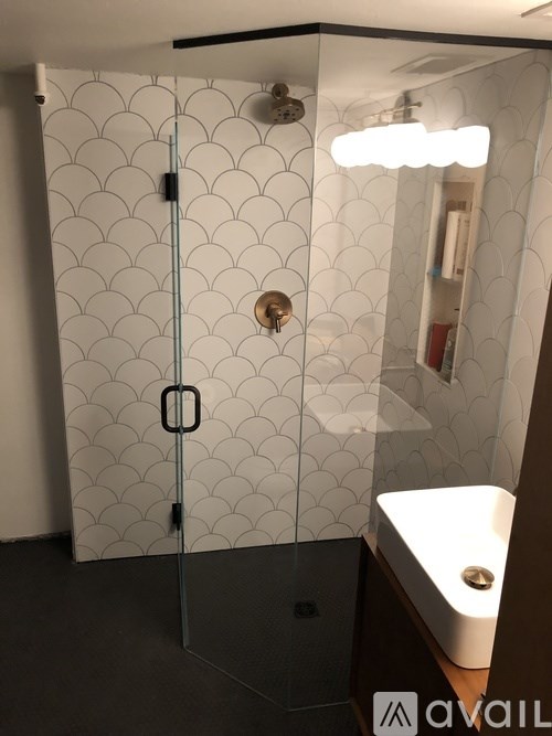 A bathroom with a white tiled shower and a glass door.