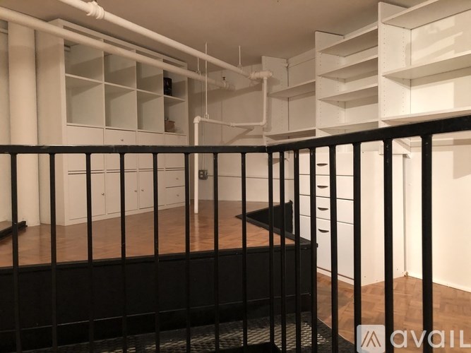 A balcony with a black railing and a white wall in the background.