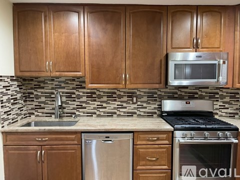 A kitchen with wooden cabinets and a stainless steel dishwasher.