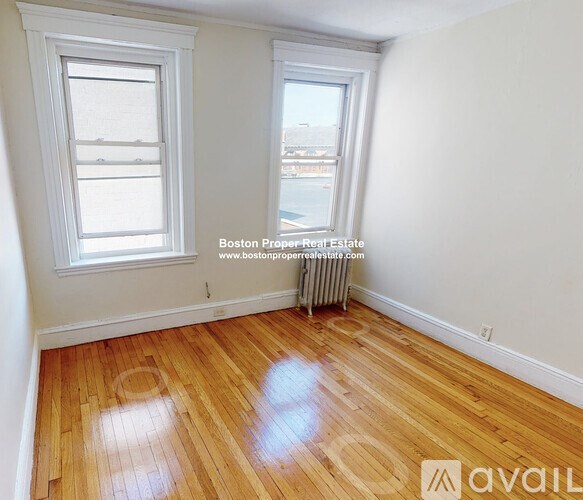 A room with wooden floors and two windows.