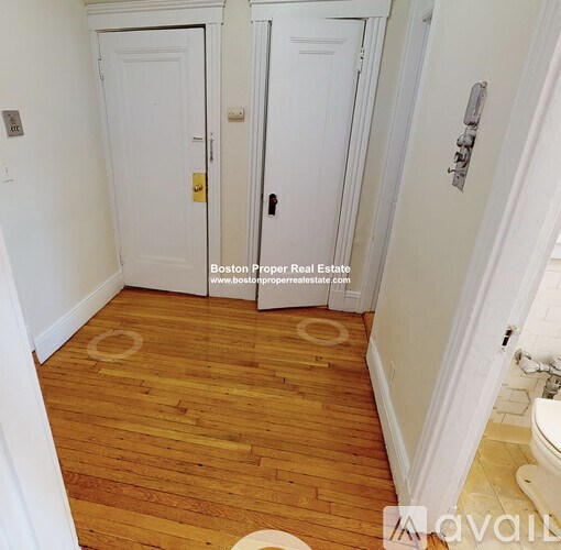A bathroom with wood floors and white walls.
