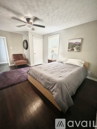 A bedroom with a bed, chair, and window.