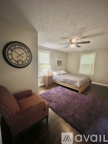 A bedroom with a bed, a couch, and a clock on the wall.