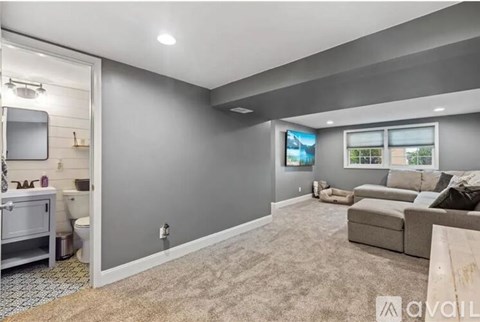 A living room with a grey carpet and a grey wall.