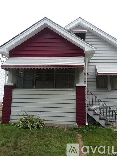 A white house with a red roof and a small porch.