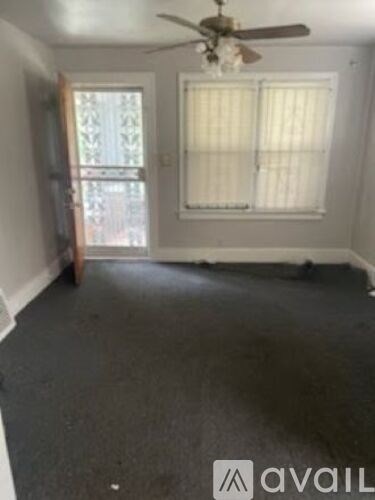 A room with a ceiling fan and a window with blinds.