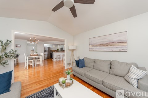 A living room with a grey couch and a ceiling fan.
