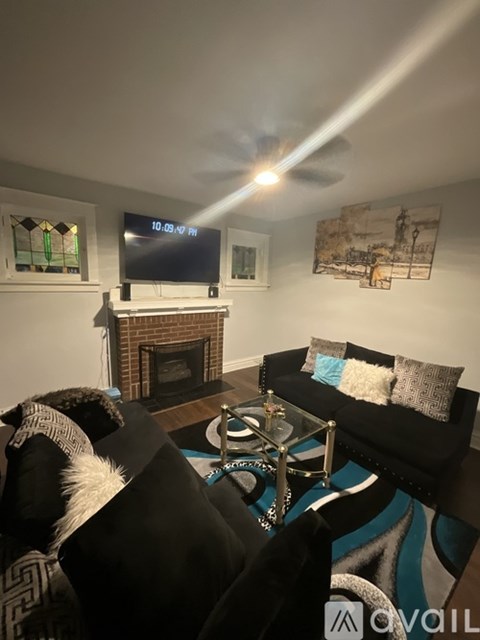 A dog is sitting on a couch in a living room with a fireplace and a television.