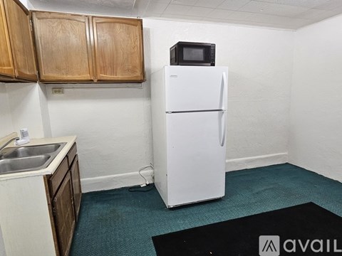 A small kitchen with a white refrigerator and wooden cabinets.